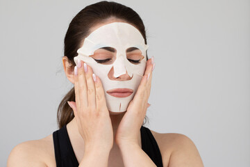 Young woman applying cosmetic face mask for skin care treatment