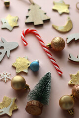 Various cute Christmas ornaments on pale pink background. Selective focus.