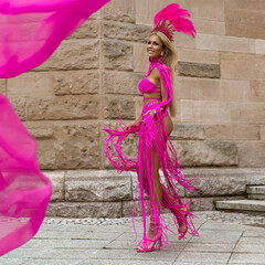 Sexy female model with long legs in sexy pink macrame dress sensually walks around the city.
