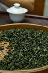 Closeup of loose green tea leaves next to a teapot, symbolizing a calming beverage ritual