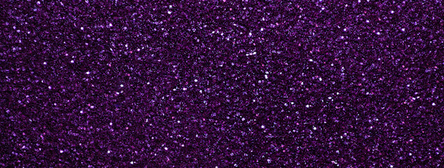 Dark violet sparkling background from small sequins, macro. Purple shiny backdrop with glitter pattern.