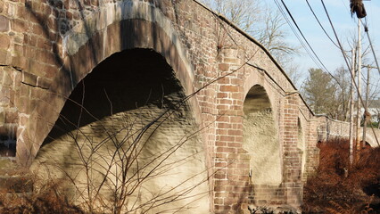 One old arched bridge cross above the river in the countryside of the USA
