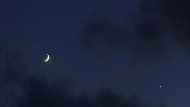 Crescent Moon and Planet Venus in Astronomical conjunction time lapse in blue night sky	
