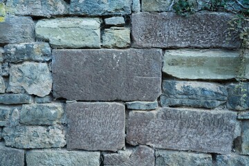 Rustikale Trockenmauer bedeckt mit grünem Efeu. Natürliche Textur und Struktur, ideal als Hintergrund für Präsentationen, Werbung und Banner. Schöne Verbindung von Natur und Architektur