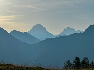 Silhouette of majestic mountain peak Mangart shrouded in veil of mist in alpine wilderness of Julian Alps, Friuli Venezia Giulia, Italy. Gentle twilight in Italian Alps. Wanderlust in Italian Alps