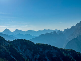On top of Jof di Miezegnot with view of silhouette of majestic mountain peaks of Julian Alps,...