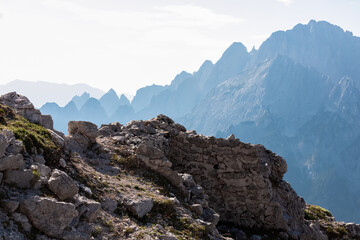 Hiking trail along remains of defensive line first world war on top of Jof di Miezegnot. Surrounded by majestic ridges of Julian Alps shrouded in misty haze, Friuli Venezia Giulia, Italy. Wanderlust