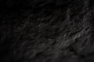 Extreme close up of painted in black handmade paper clay with a structure and rough texture. Paper recycling. Selective focus, shallow depth of field.