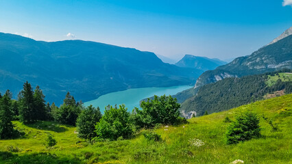 Obraz premium Aerial view of alpine lake Lago di Molveno in mountain retreat town Molveno, Trentino, Italy. Surrounded by forest, alpine meadows and mountain peaks Brenta Dolomites. National Park Andalo Paganella