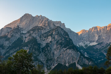 Scenic view of stunning mountain peak Jof Fuart bathed in soft glow of twilight. Massive rugged...