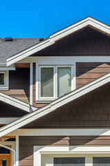 Top of grey stucco luxury house with shingle roof, red and yellow trees and nice windows in Summer in Vancouver, Canada, North America. Day time on June 2024.