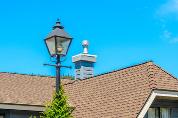 Top of grey stucco luxury house with shingle roof, red and yellow trees and nice windows in Summer in Vancouver, Canada, North America. Day time on June 2024.