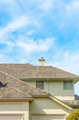 Top of grey stucco luxury house with shingle roof, red and yellow trees and nice windows in Summer...