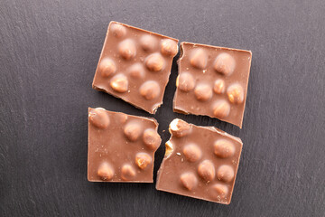 Dark chocolate with hazelnuts on slate stone, close-up, top view.