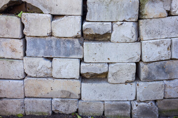 Close-up of an old, weathered brick wall with visible damage and wear.  Irregular shapes and colors show age and decay.