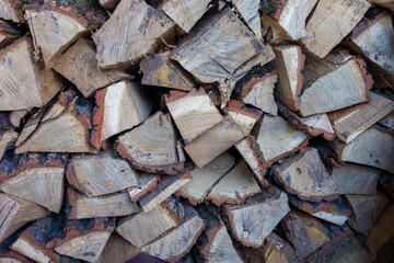 A stack of neatly arranged firewood, ready for winter.  Various sizes and shades of wood are visible.