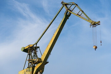 Large green crane protruding into the sea. Blue sky background