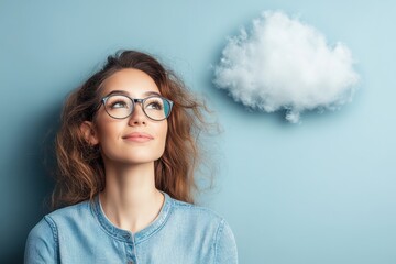 Young woman with glasses looking thoughtfully at a cloud on a blue wall background