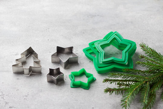 Assorted Christmas cookie cutters with Christmas tree branches on grey textured background