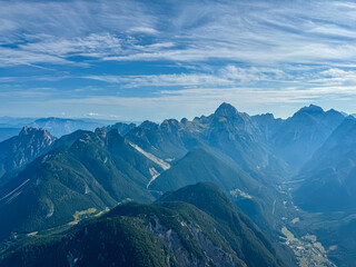 Fototapeta premium Aerial view of Upper Soca Valley surrounded by majestic mountain peaks of Western Julian Alps. On top of Cima Del Lago on border Italy Slovenia, Triglav National Park. Wanderlust in alpine wilderness