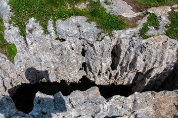 Close-up view of rocky terrain with deep, dark crevice cutting through. Rock surface is rough and textured, with various holes and indentations. Brenta Dolomites, Trentino, Italian Alps, Italy