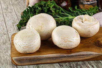 White champignon mushrooms heap over board