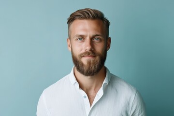 Obraz premium Confident Young Man with Beard Posing Against a Soft Blue Background