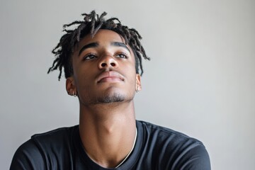 Obraz premium Contemplative Young Man with Dreadlocks Gazing Upward in Natural Light