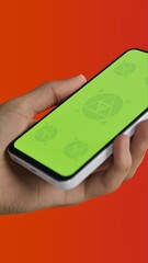 Asian young male using smartphone with a blank green screen. Mobile app video mockup. Vertical phone orientation
