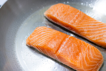 Fresh raw salmon fillets cooking on skillet
