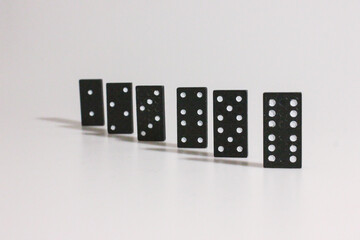 Black domino figures stand in a row on a white background. Board games. Family entertainment. Excitement. Victory. Poster and background