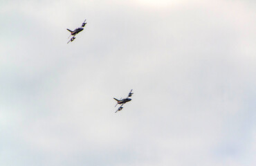 Two jet aircraft captured mid-air, flying in a synchronized formation against a cloudy sky. A...