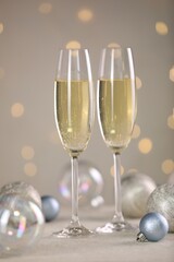 Delicious champagne in glasses and Christmas decor on white table against blurred lights
