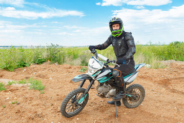 A man in motorcycle equipment sits on an enduro motorcycle.