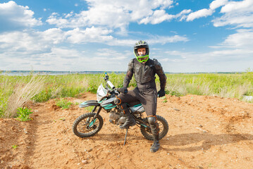 A man in motorcycle equipment sits on an enduro motorcycle.