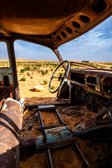 A wrecked car abandoned in the desert.