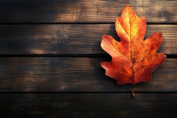 Obraz premium A single, vibrant autumn leaf rests on a dark wooden surface, evoking the season's beauty.