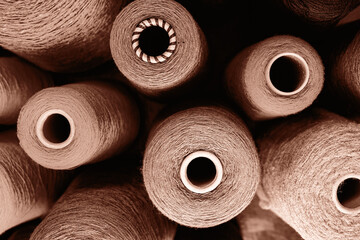 Close-up image showcasing multiple yarn spools in an array of earthy tones. Demonstrating color of...