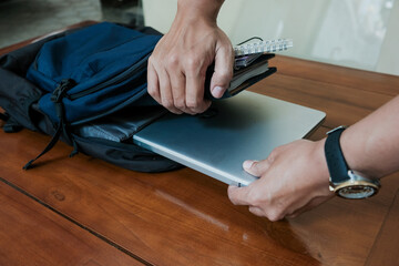 Closeup of hand man holding laptop on inside Blue backpack with books and notepad inside for...