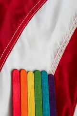 abstract rainbow color sticks arranged against an american flag red and white stripes background lgbtq pride
