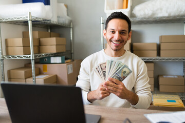 Entrepreneur managing online store and holding us dollar banknotes earned with laptop orders