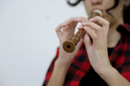 
Young caucasian woman playing recorder on white background with copy space.