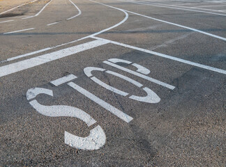 Stop sign white painted on the road asphalt with horizontal signs white painted stripes on the road
