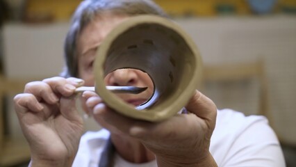 An artisan potter presents a unique handmade clay cylinder with intricate design and craft. Stock Clip