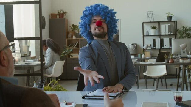 Funny clown in formal suit shaking hands with boss, taking business papers, then walking to his desk and pretending to work on laptop in office