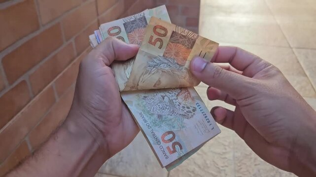 Real currency, money from Brazil. Brasil, Dinheiro, Reais, Hand. People holding in hand a brazilian banknotes.