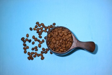 Coffee beans and wooden cup isolated on blue background