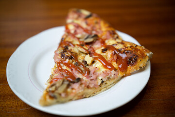 Slice of pizza with ketchup on a white plate