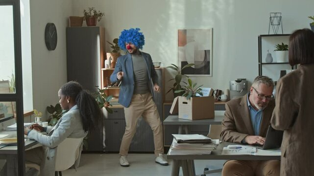 Happy businessman dancing in office, removing clown wig and nose, showing resignation letter to surprised colleagues and walking away with proud smile while quitting boring job