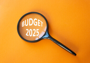 Budget 2025 symbol. Magnifying Glass with words Budget 2024. Beautiful orange background. Business and Budget 2025 concept. Copy space.